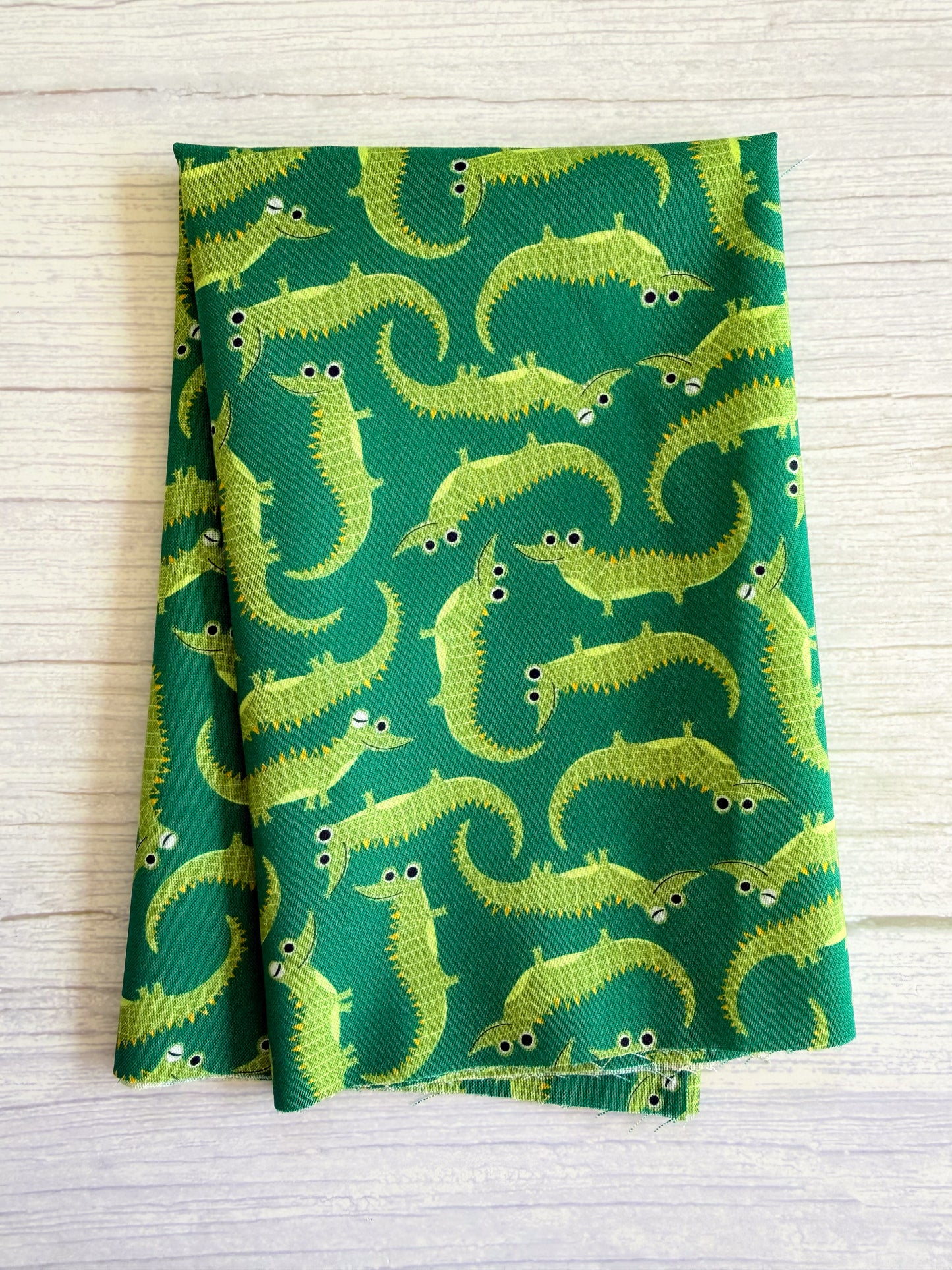 Green fabric with yellow alligator pattern on a wooden surface