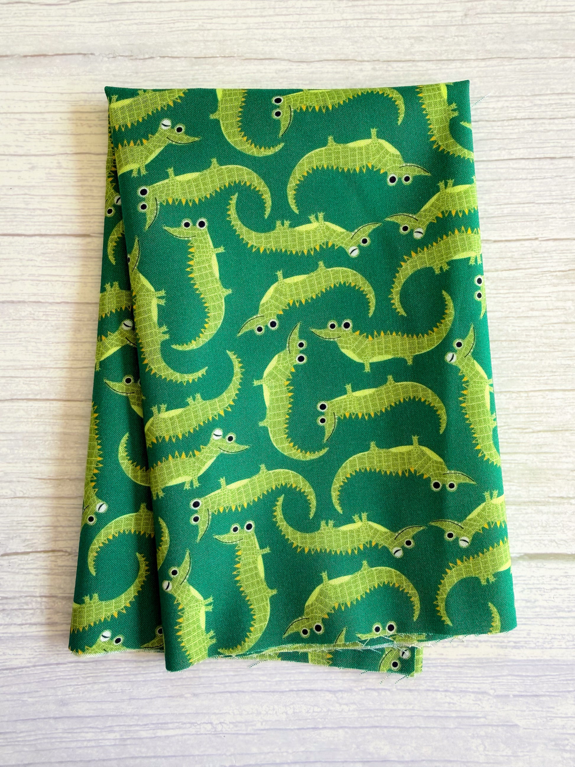 Green fabric with yellow alligator pattern on a wooden surface