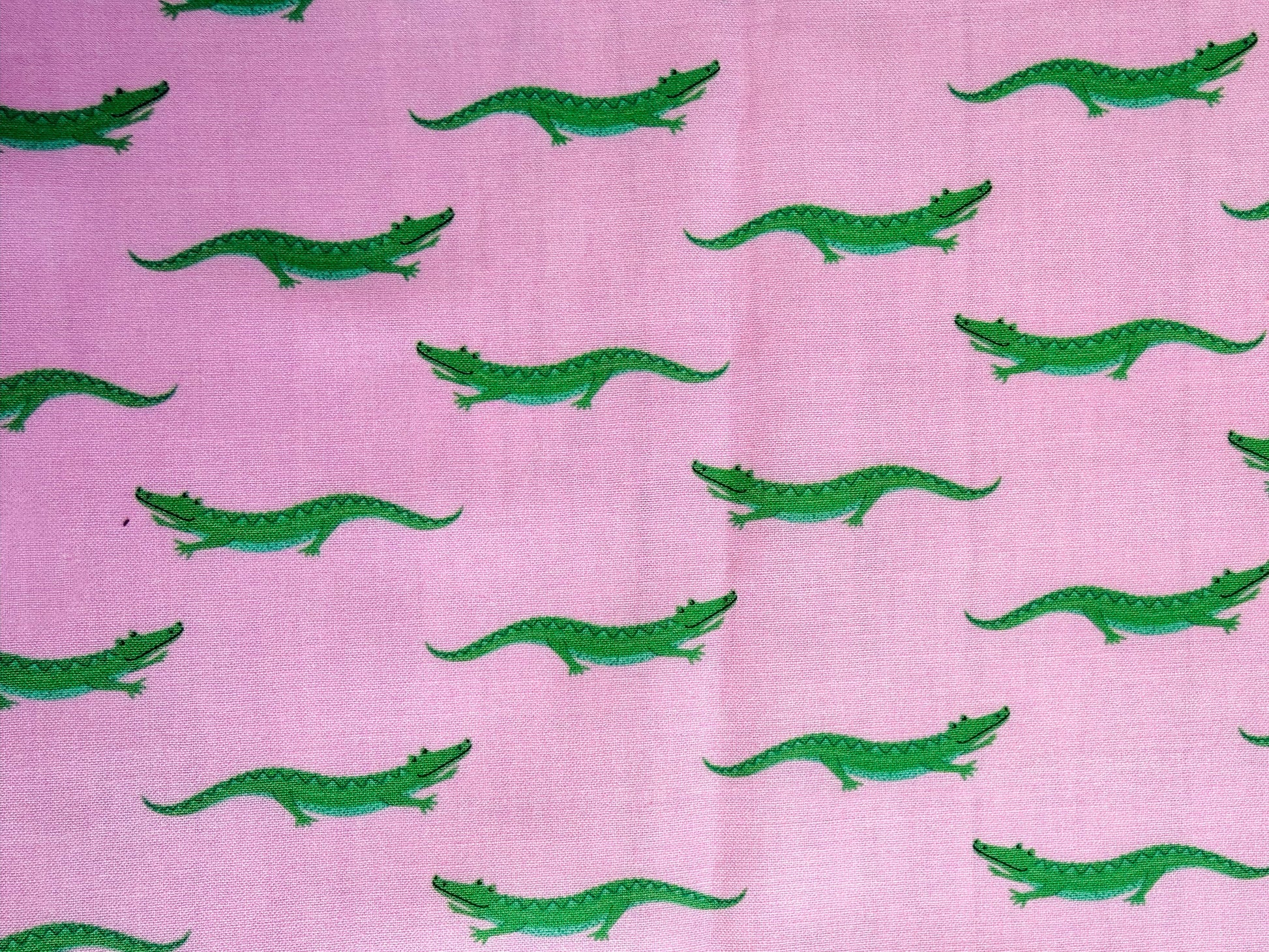 Green crocodile pattern on a pink background