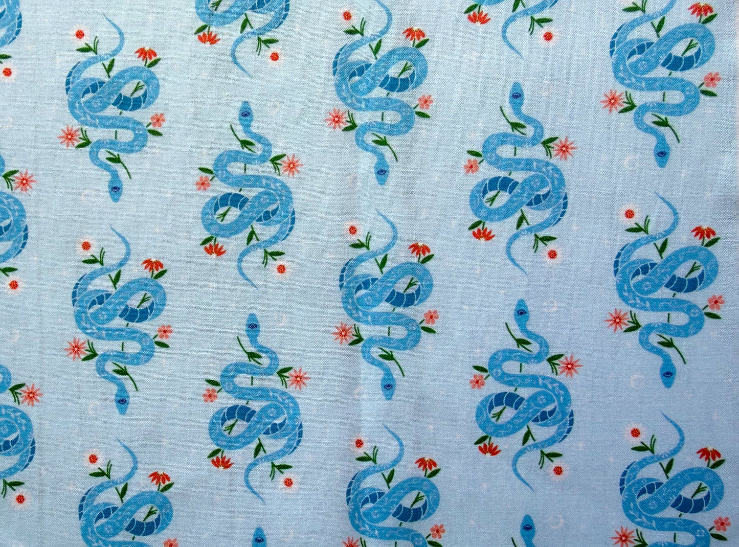 Pattern of blue snakes and flowers on a light blue background