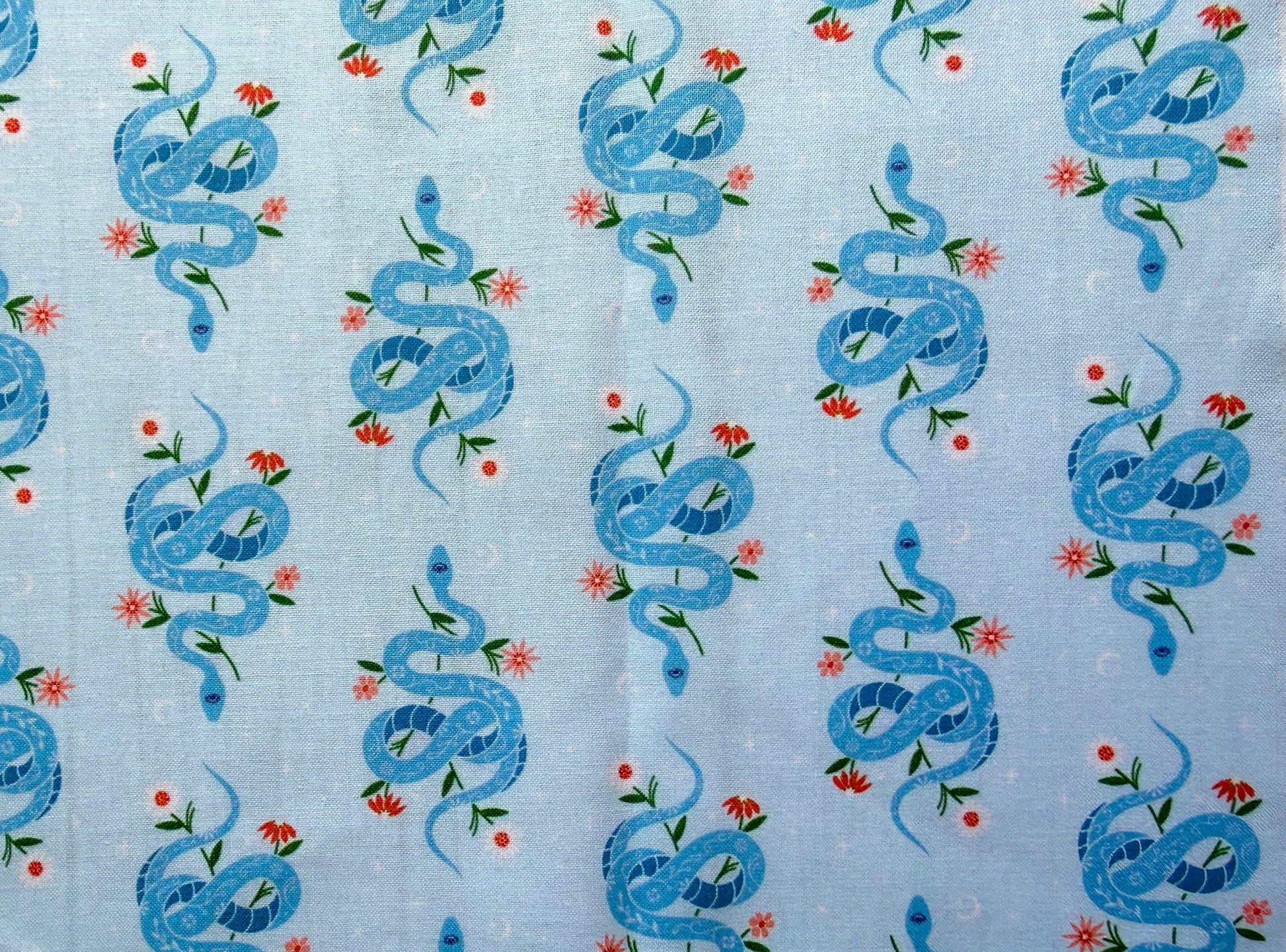 Pattern of blue snakes and flowers on a light blue background