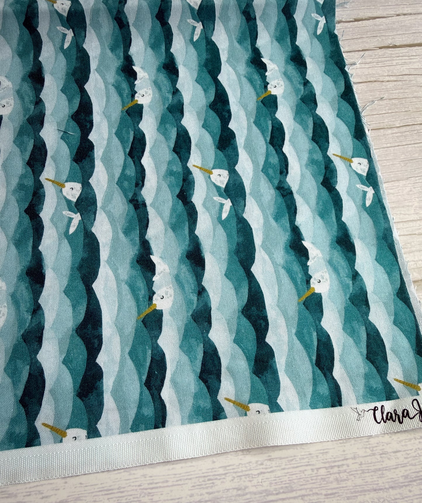 Patterned fabric with wavy lines and small narhwals on a wooden surface