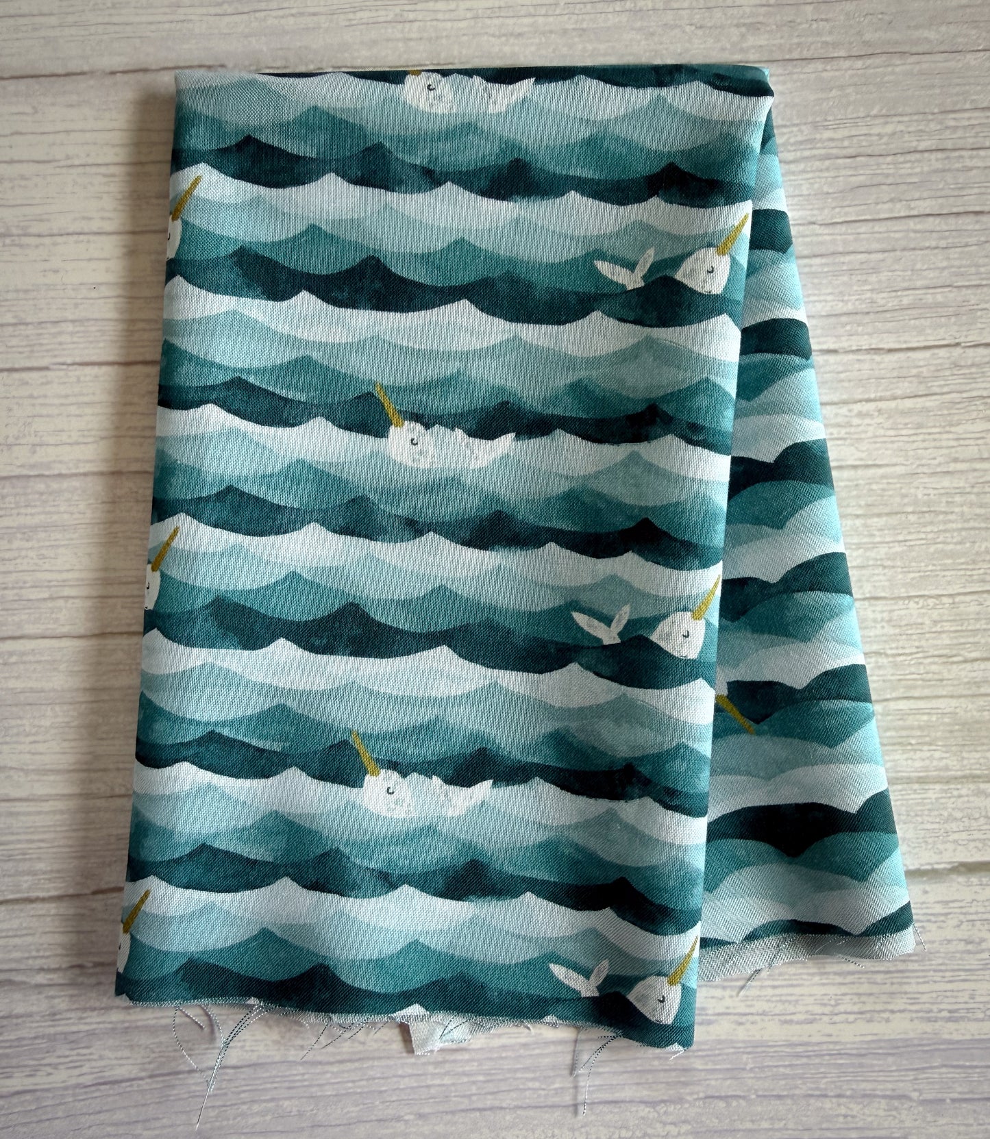 Folded fabric with narwhal pattern on a wooden surface