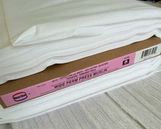 Roll of wide perm press muslin with a pink label on a gray surface